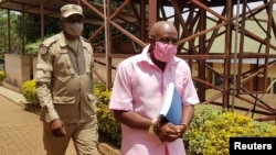 FILE - Paul Rusesabagina, portrayed as a hero in a Hollywood movie about Rwanda's 1994 genocide, is escorted in handcuffs from the courtroom in Kigali, Rwanda, Sept. 25, 2020. 
