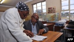 South African musician, Sipho 'Hotstix' Mabuse (R), 60, talks with a classmate as he attends class in a school in Soweto, April 25, 2012.