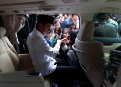 Indonesian President Joko Widodo, center, hands out books to children during his visit to Tanah Tinggi, a lower-income neighborhood, in Jakarta, Indonesia, July 26, 2019.