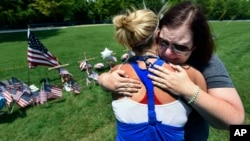 Sophia Ensley, left, comforts Barbie Branum by a makeshift memorial at the entrance to the Naval Operational Support Center and Marine Reserve Center in Chattanooga, Tennessee, July 18, 2015.