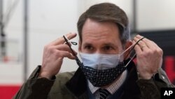 Congressman Jim Himes adjusts his two masks during a tour of a vaccination clinic, Feb. 10, 2021, at a high school in Bridgeport, Conn.