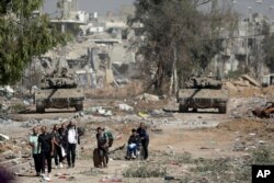 FILE - Palestinians flee to northern Gaza as Israeli tanks block the Salah al-Din road in the central Gaza Strip on Nov. 24, 2023.