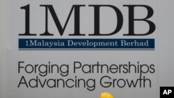 FILE - Construction workers chat in front of a billboard for state investment fund 1 Malaysia Development Berhad (1MDB) at the fund's flagship Tun Razak Exchange development in Kuala Lumpur, Malaysia, May 14, 2015.
