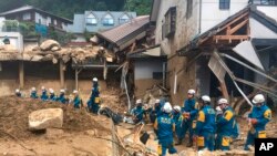 Emergency teams rest outside of structural damage caused by heavy rains, Monday, July 9, 2018, in Hiroshima, Japan. (AP Photo/Haruka Nuga)