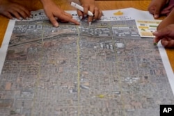 Residents look at a map of central Phoenix to find locations for a cool corridor at an event hosted by Arizona State University graduate design students at Academia del Pueblo charter school, Friday, Sept 28, 2022, in Phoenix. Community members were learning how to organize and advocate for cooler, greener, healthier neighborhoods. (AP Photo/Matt York)