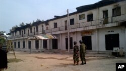 Tentara Nigeria berjaga di luar sebuah pertokoan yang terbakar di Maiduguri, Nigeria (8/10).