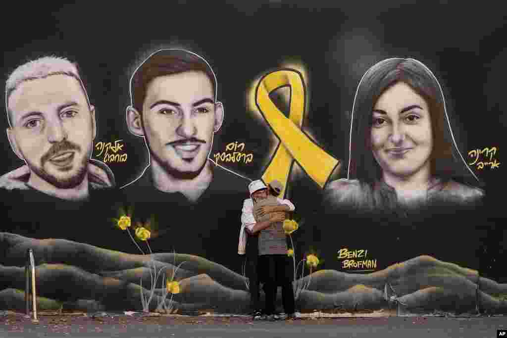 People hug next to graffiti portraits of Gaza-held hostages in Jerusalem.&nbsp;(AP Photo/Ohad Zwigenberg)