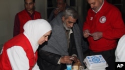 Anggota Palang Merah Suriah memberikan makanan dan minuman.