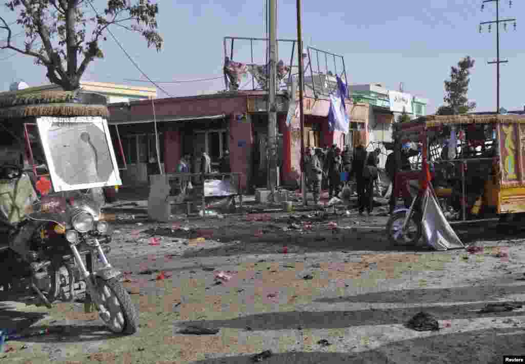 People stand near debris at the site of a suicide blast in Faryab, Afghanistan, March 18, 2014. 