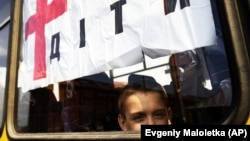 A boy from Siversk, Ukraine, looks though the window of a bus during evacuation near Lyman, Donetsk region, May 11, 2022. (Evgeniy Maloletka/AP)