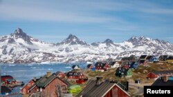 FILE - Snow-covered mountains rise above the harbor and town of Tasiilaq, Greenland, June 15, 2018. 