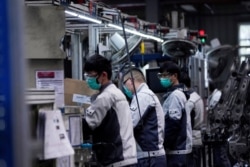 FILE -- Employees wearing face masks work on a car seat assembly line at Yanfeng Adient factory in Shanghai, China, as the country is hit by an outbreak of a new coronavirus, February 24, 2020.
