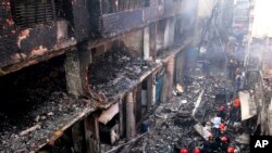 Penduduk setempat dan petugas pemadam kebakaran berkumpul di sekitar bangunan yang hangus akibat kebakaran di Dhaka, Bangladesh, 21 Februari 2019.