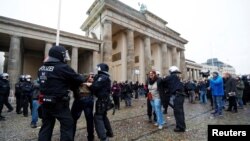Demonstrators are detained by police officers during a protest against the government's coronavirus disease (COVID-19) restrictions, next to the Brandenburger Gate in Berlin, Nov. 18, 2020.