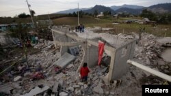 Residents stand next to debris after fireworks stored in a house exploded in San Isidro, Chilchotla, Mexico, May 9, 2017. 