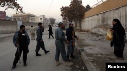 A woman talks to Afghan policemen near the site of a suicide attack that wounded Afghanistan's Intelligence Chief Asadullah Khalid, Kabul, Dec. 6, 2012.