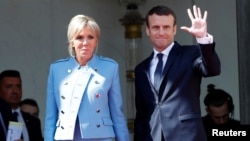 French President Emmanuel Macron and his wife, Brigitte Trogneux, wave to former President Francois Hollande as he leaves after the handover ceremony at the Elysee Palace in Paris, May 14, 2017.