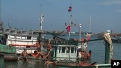 Cambodian workers use barrels to float a fishing boat which just hauled from the Gulf of Thailand.