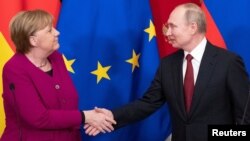Presiden Rusia Vladimir Putin dan Kanselir Jerman Angela Merkel berjabat tangan setelah konferensi pers bersama di Kremlin, Moskow, Rusia, 11 Januari 2020. 