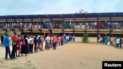 Watu wakisubiri kwenye foleni kufunguliwa kwa kituo cha kupigia kura katika uchaguzi wa rais mjini Libreville, Agosti 26, 2023.