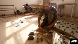 FILE - Members of the Kurdish People's Protection Units (YPG) take position in a classroom in the village of Maarouf in the northeastern Syrian province of Hasakeh as they battle Islamic State group jihadists, July 16, 2015.