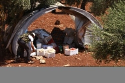FILE - A Free Syrian Army member inspects goods that were confiscated at a checkpoint during a siege on the Kurdish city of Afrin, in the Aleppo countryside, June 30, 2013.