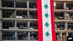 Bendera Lebanon terpampang di sebuah gedung yang rusak dekat lokasi ledakan pekan lalu di pelabuhan Beirut, Lebanon, Rabu, 12 Agustus 2020. (Foto: AP Photo/Hassan Ammar)