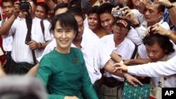 Burma's pro-democracy leader Aung San Suu Kyi greets supporters as she leaves her National League for Democracy party following her meeting with newly elected lawmakers at the party headquarters in Rangoon, April. 7, 2012.