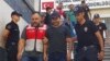 Turkish police officers escort Turkish pop singer Atilla Tas, center, to police headquarters following his arrest, in Istanbul. Tas and 28 other people, mostly journalists, went on trial Monday, March 27, 2017, on terrorism charges for alleged links to a failed coup attempt. 