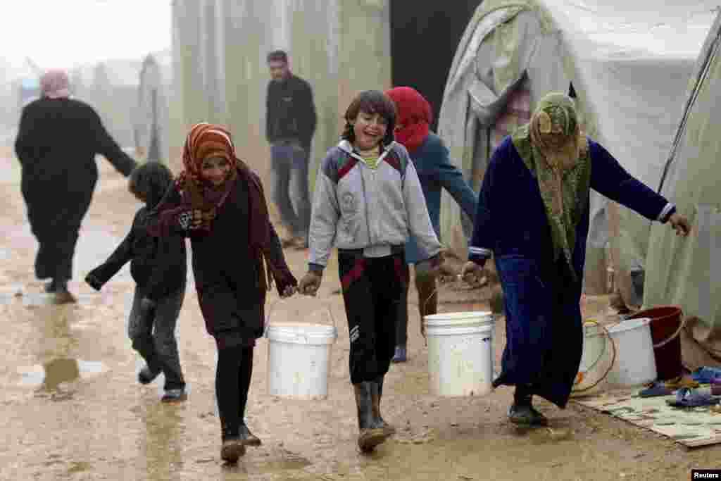 Internally displaced people carry buckets of water as they walk during the cold weather in Jerjnaz camp, in Idlib province, Syria.