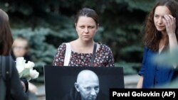 A woman holds a portrait of journalist Aleksandr Rastorguyev during funeral ceremony in Moscow, August 7, 2018