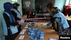 Para pegawai pemilu di Afghanistan menghitung kertas suara di sebuah TPS di provinsi Herat (5/4).