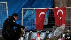 FILE - A police officer looks a photographs of the victims displayed a day after an attack at a popular nightclub in Istanbul, Jan. 2, 2017.