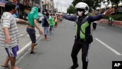 A traffic officer instructs jobless jeepney drivers to practice social distancing as they line up to receive food donations during the lockdown in Quezon city, Philippines on Aug. 7, 2020. 