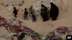 In this March 14, 2019, file photo, Women and their children who left the besieged Islamic State-held village of Baghouz, Syria, scramble over a rocky hillside to be checked by U.S-backed Syrian Democratic Forces. (AP Photo/Maya Alleruzzo, File)