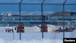 2025년 2월 17일 비상요원들이 캐나다 온타리오주 미시소거의 토론토 피어슨 국제공항에서 비행기 추락 사고 후 활주로에서 비행기 주변을 정리하고 있다.