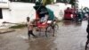 Un homme transporte des gens dans une charrette dans une rue inondée de Tuléar, à Madagascar, un jour après le passage du cyclone Haruna, 23 février 2013.