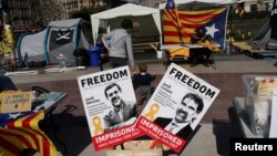 FILE - Banners with the photos of jailed Catalan pro-independence leaders Jordi Sanchez and Jordi Cuixart are displayed at a protest rally in Barcelona, Spain, March 28, 2018.