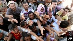 Displaced Iraqis from the Yazidi community gather for humanitarian aid at the Syria-Iraq border at Feeshkhabour border point, northern Iraq, Aug. 10, 2014.