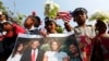 A girl holds a portrait of U.S. President Barack Obama and his family during a rally in front of the U.S Embassy in Phnom Penh, March 17, 2015.