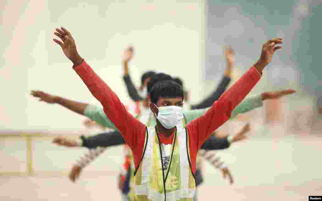 Pekerja bangunan di Singapura memakai masker wajah untuk melindungi diri dari kabut asap saat melakukan senam pagi sebelum bekerja.