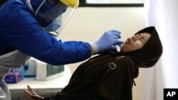 Seorang perempuan bereaksi ketika seorang petugas akan melakukan test Swab Covid-19 di Tanah Abang, Jakarta (foto: ilustrasi).