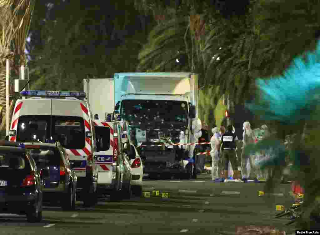 Pasukan polisi Perancis dan petugas forensik berdiri dekat truk yang menabrak kerumunan massa di Nice, Perancis (15/7). (Reuters/Eric Gaillard)