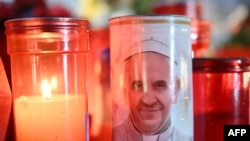 Candles are lit at the statue of John Paul II outside the Gemelli University Hospital where Pope Francis is hospitalized with pneumonia, in Rome on March 04, 2025.