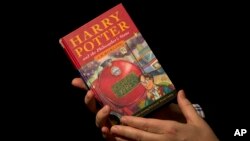 FILE - Sotheby's director of the department of printed books and manuscripts holds a first edition copy of the first Harry Potter book "Harry Potter and the Philosopher's Stone" containing annotations and illustrations by author J.K. Rowling, May 20, 2013.