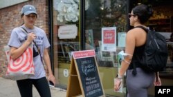 FILE - People walk past a "We're hiring" sign posted at a store in New York City, Aug. 20, 2021.