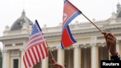 지난 2019년 2월 도널드 트럼프 미국 대통령과 김정은 북한 국무위원장의 정상회담이 열린 베트남 하노이 메트로폴 호텔에서 두 정상의 도착을 기다리는 주민이 미국 성조기와 북한 인공기를 나란히 들고 있다. (자료사진)