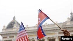 지난 2019년 2월 미-북 정상회담이 열린 베트남 하노이 메트로폴 호텔에서 두 정상의 도착을 기다리는 주민이 미국 성조기와 북한 인공기를 나란히 들고 있다.