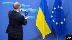 A member of a delegation takes a photo with his cellphone of the Ukrainian and EU flags after an EU summit in Brussels, March 6, 2014.