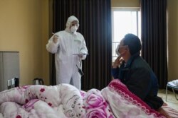 A doctor (L) talks with a patient during his rounds at the ward of a quarantine zone in Wuhan, the epicenter of the new coronavirus outbreak, in China’s central Hubei province, Feb. 3, 2020.